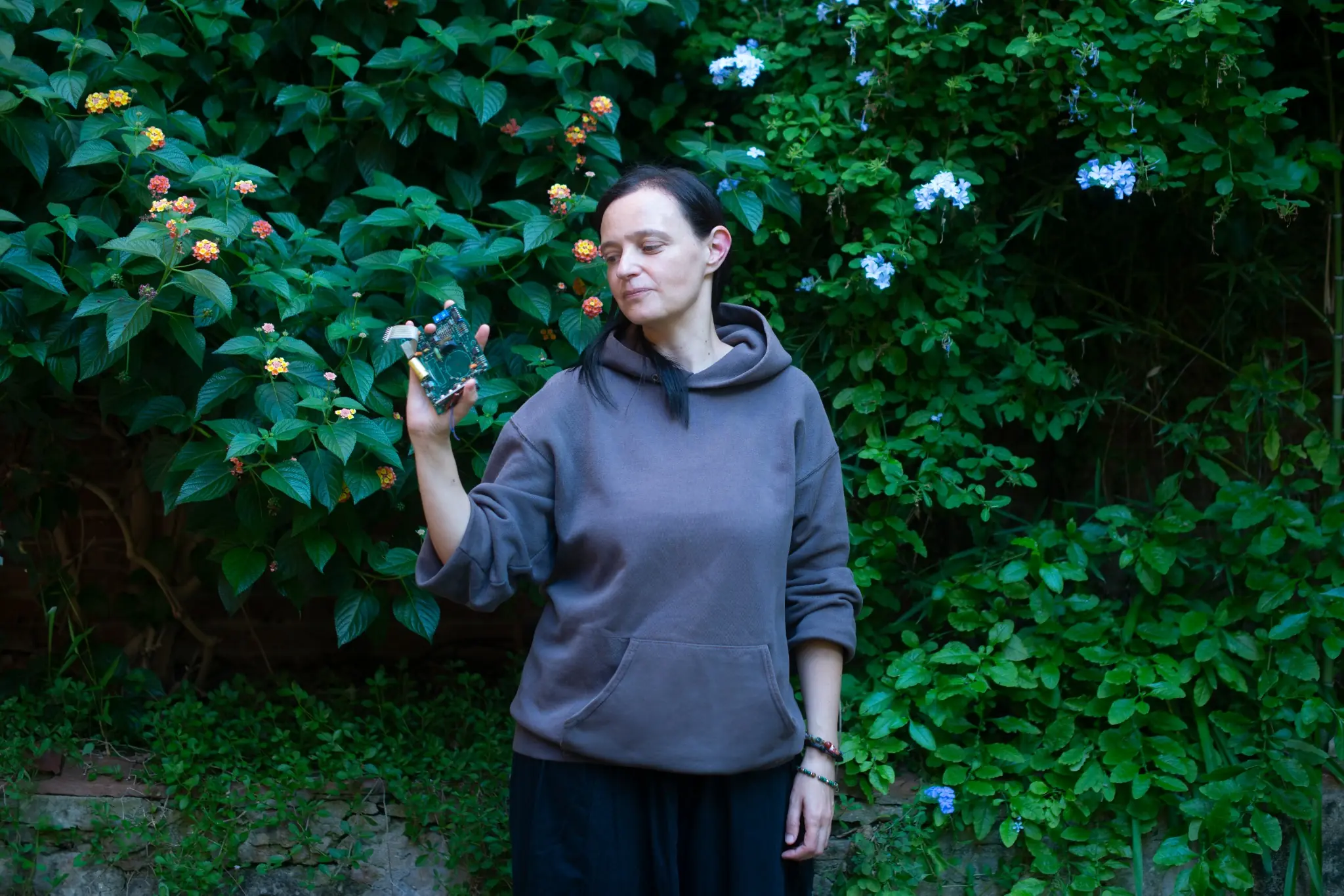 foto di stefania che guarda un circuito che tiene in mano con uno sfondo di piante verdi